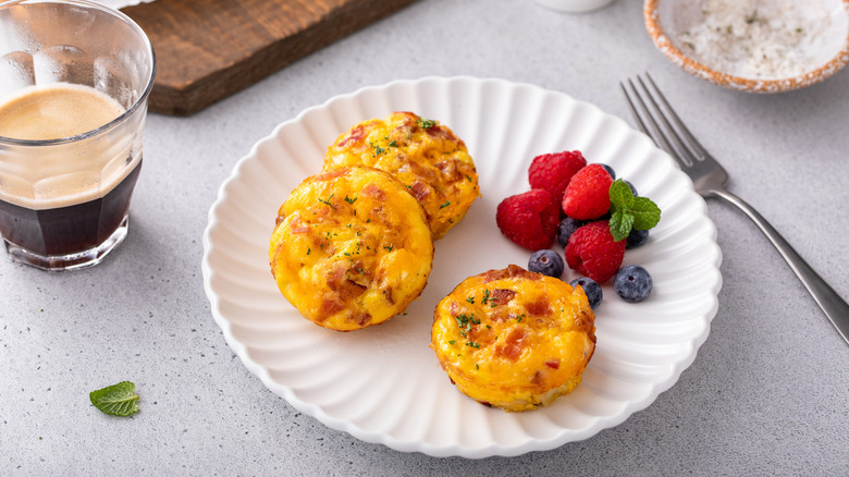 Three egg bites on a white plate with berries.