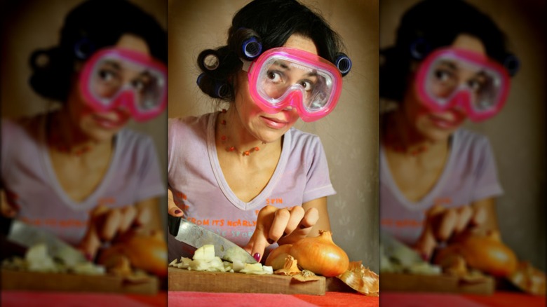 Woman wears goggles chopping onions