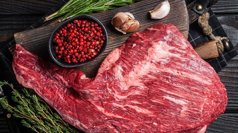 raw tri-tip on a cutting board surrounded by herbs and spices