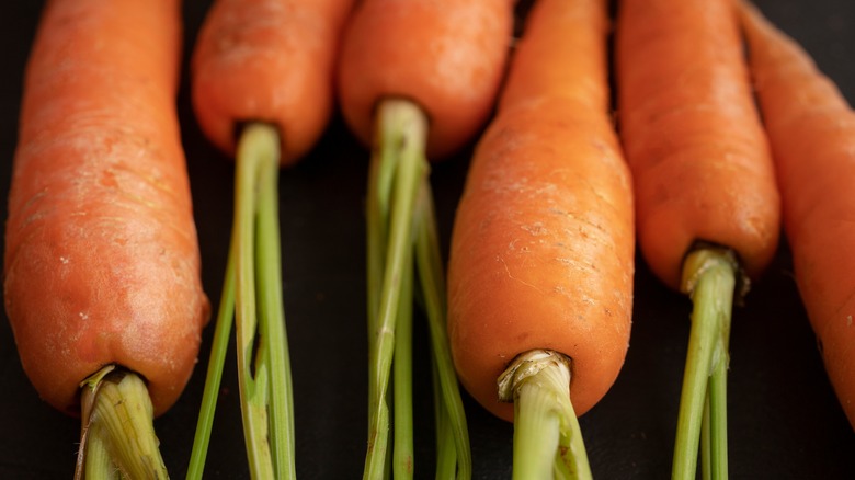 Unpeeled carrots on black background