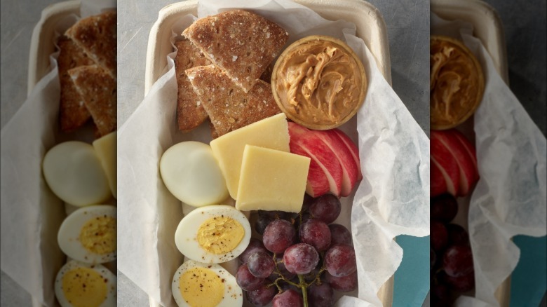 Peanut butter board with fruit, eggs, and cheese