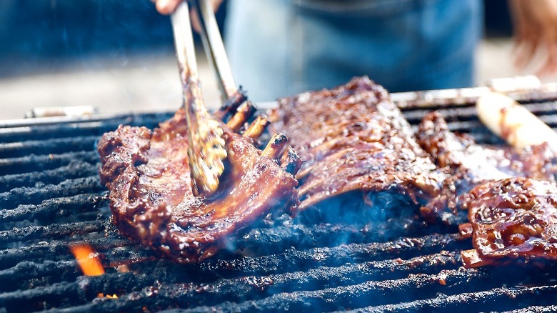 person flipping ribs on an outdoor grill