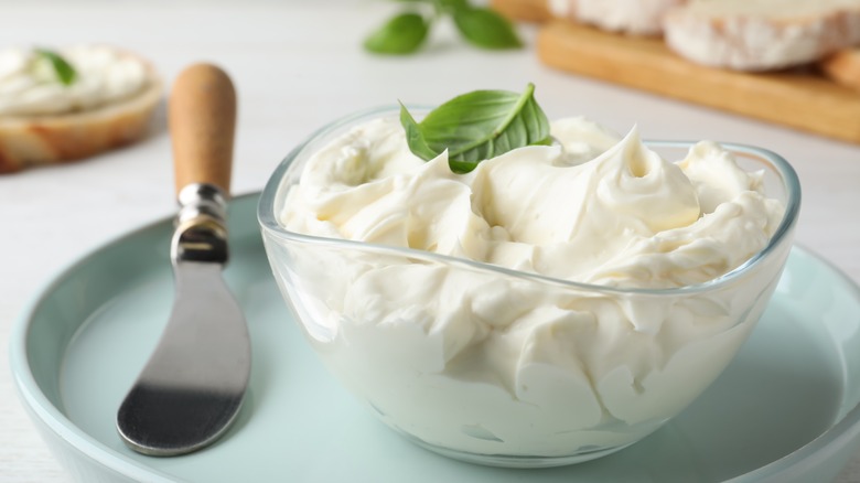 A bowl of cream cheese with a knife