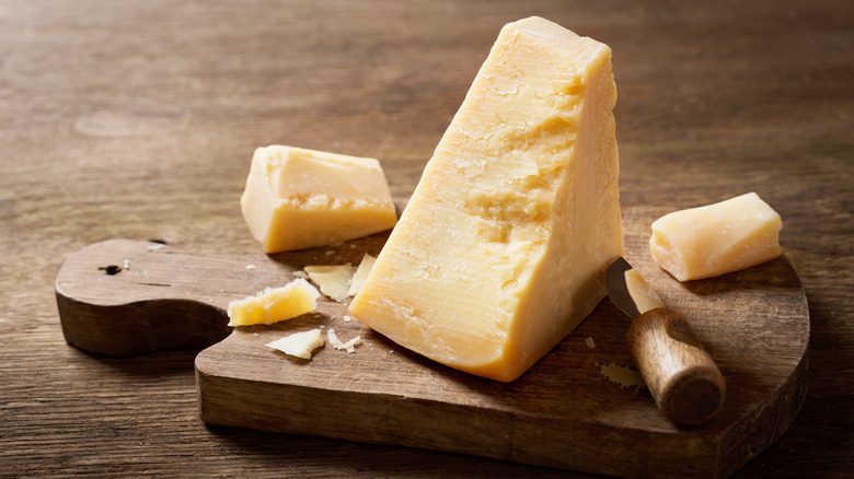 Block of parmesan cheese on a wooden cutting board