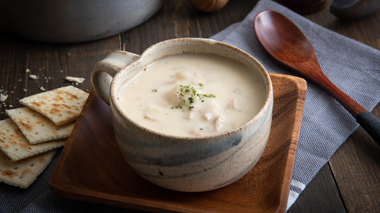 Mug of clam chowder with wooden spoon