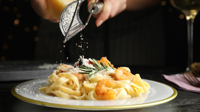 Parmesan cheese grated over a plate of pasta with shrimp