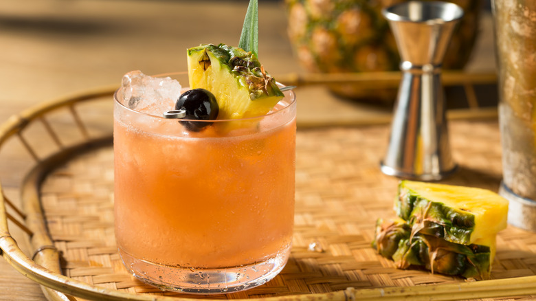 Peach-colored cocktail garnished with pineapple