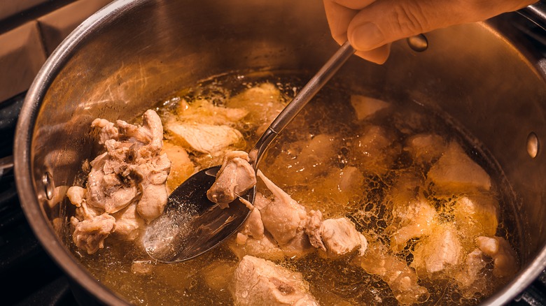 Chicken broth and meat being stirred in a pot