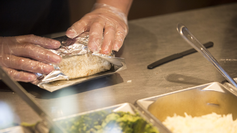 Chipotle employee folding burrito