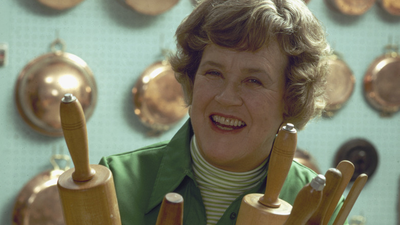 Julia Child smiling holding rolling pins