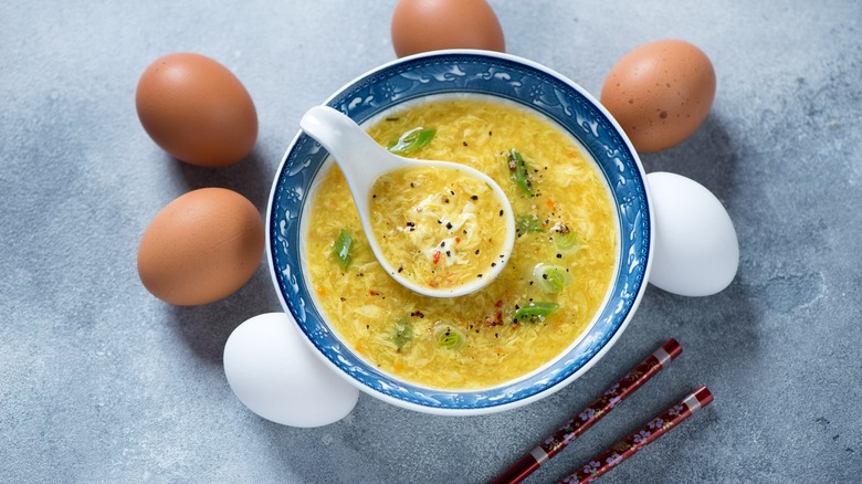 egg drop soup with chopsticks from above surrounded by fresh eggs