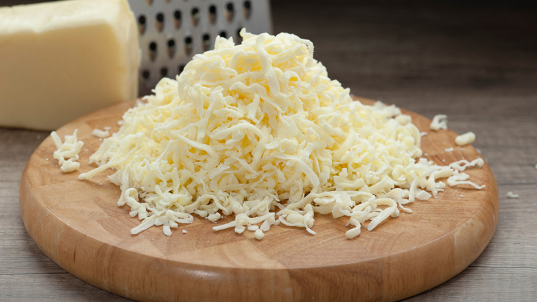 shredded mozzarella cheese on cutting board