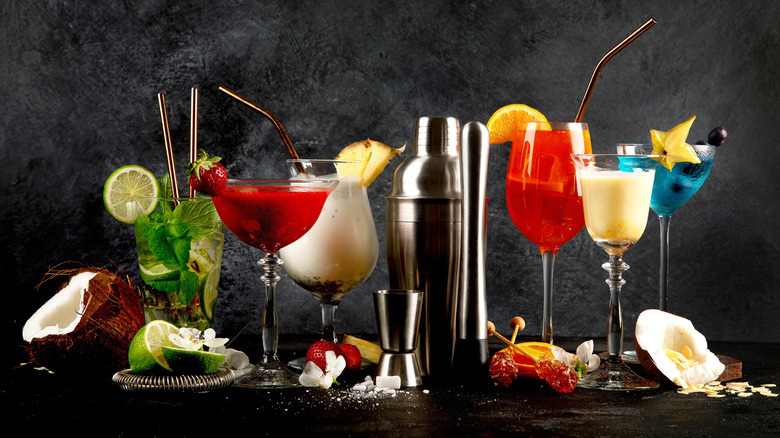 various cocktails and garnishes on grey background