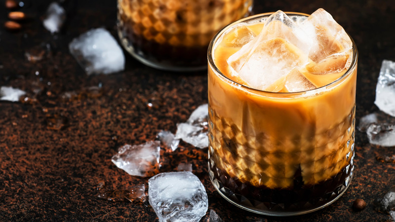 White Russian with ice cubes on coffee grounds