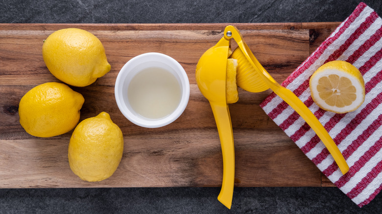 lemons on a wooden cutting board with a citrus presser