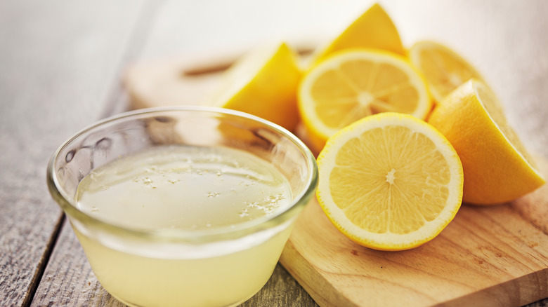 cut lemons with a container of lemon juice
