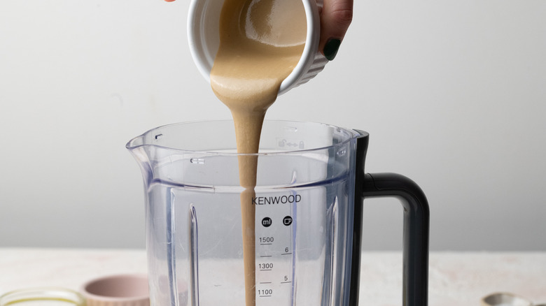 tahini being poured into blender to make hummus