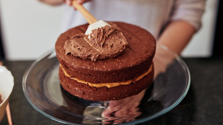 person frosting a cake