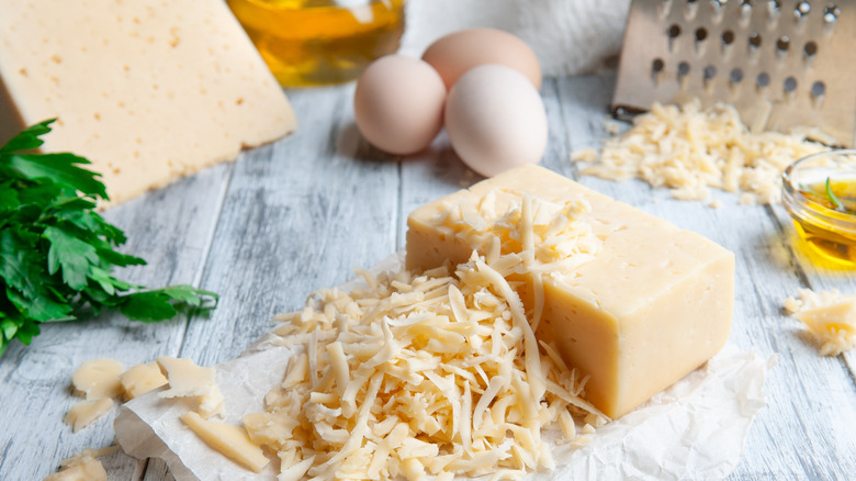 Freshly grated cheese and block of cheese on a kitchen counter