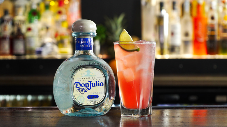 Bottle of Don Julio tequila on a bar with a margarita cocktail