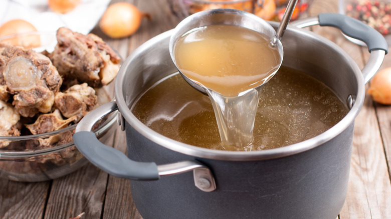 Chicken broth in pot with ladle