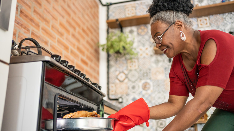 Woman removing chicken from oven