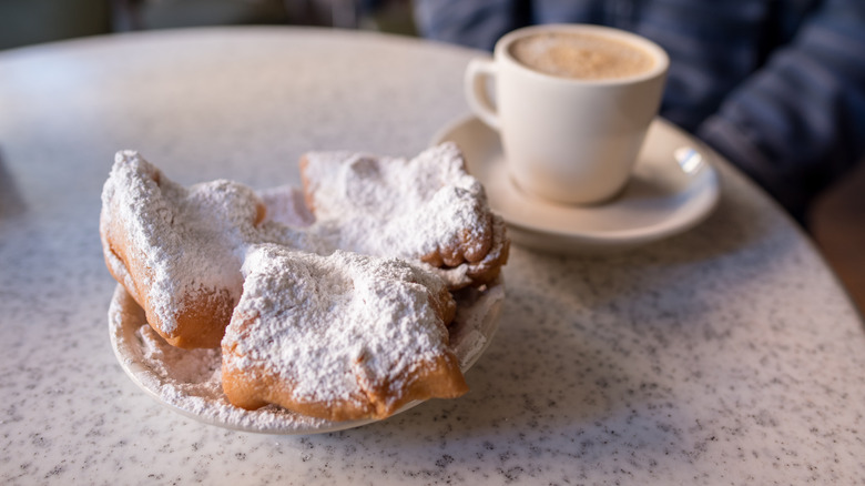 A plate of beignets next to coffee