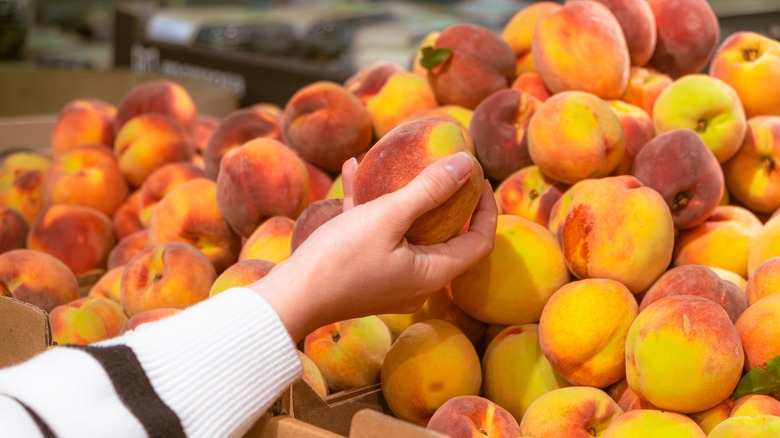 hand taking grocery store peach