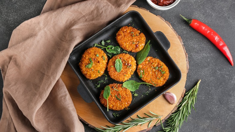 Five veggie burgers on black plate