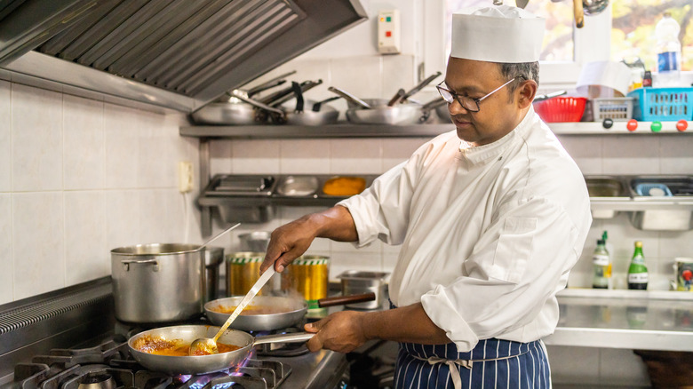 chef cooking pan sauce in a professional kitchen