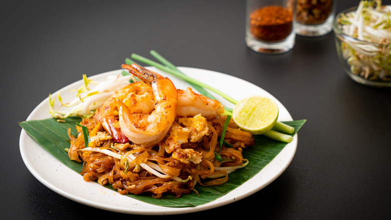 A plate of pad Thai noodles with shrimp with fresh bean sprouts, lime, and green onions