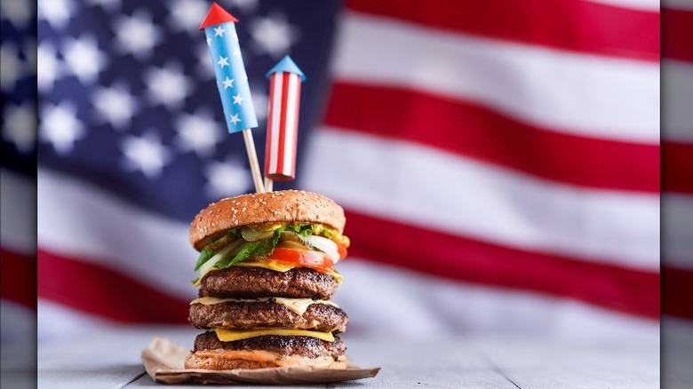 A tall burger in front of an American flag 