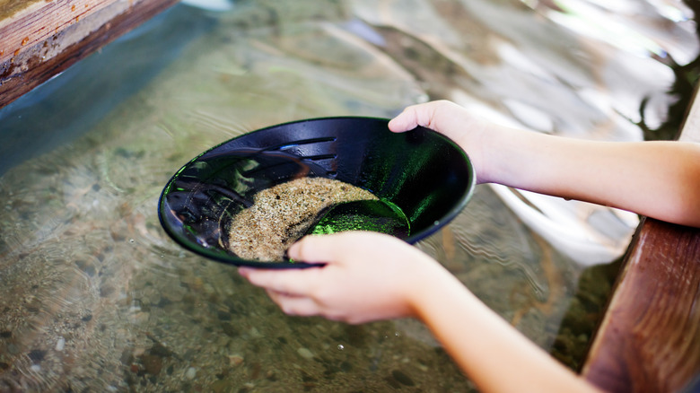 Two hands pan water for gold