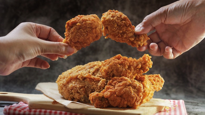 Hands holding crispy fried chicken