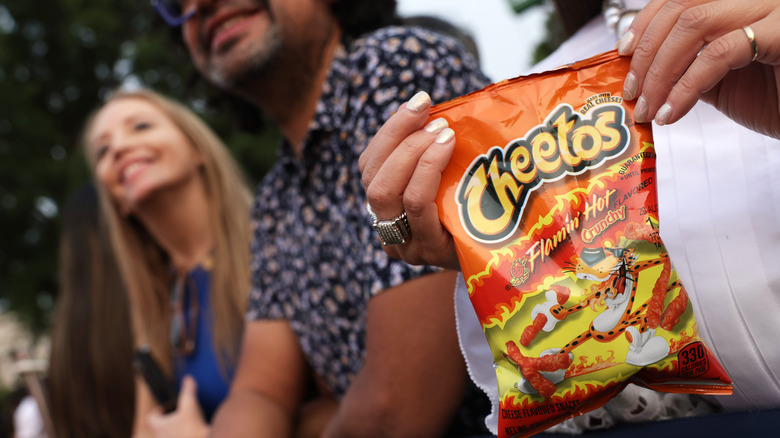 person holding bag of flamin hot cheetos