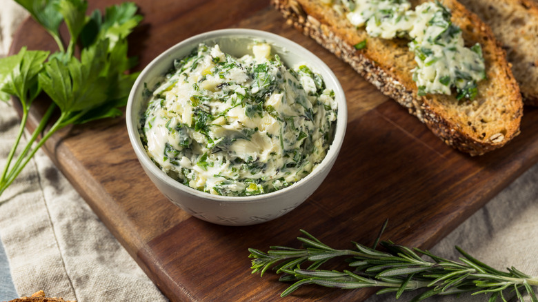 a dish of herbed butter with toasted bread