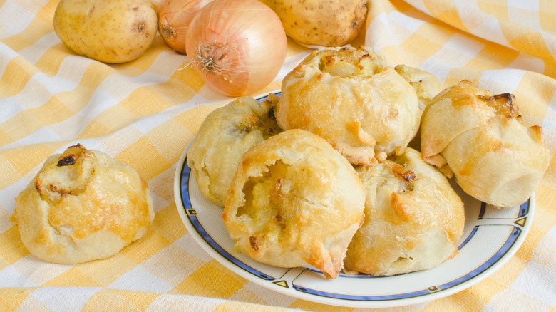 Knishes and onions on a yellow and white cloth