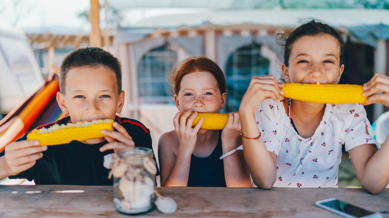 kids eating corn on the cob at picnic table