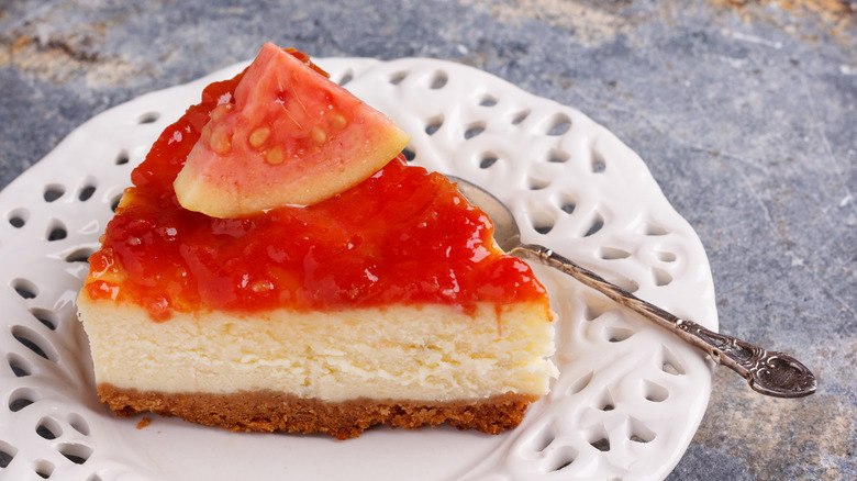 A slice of guava cheesecake with a piece of guava fruit on top.