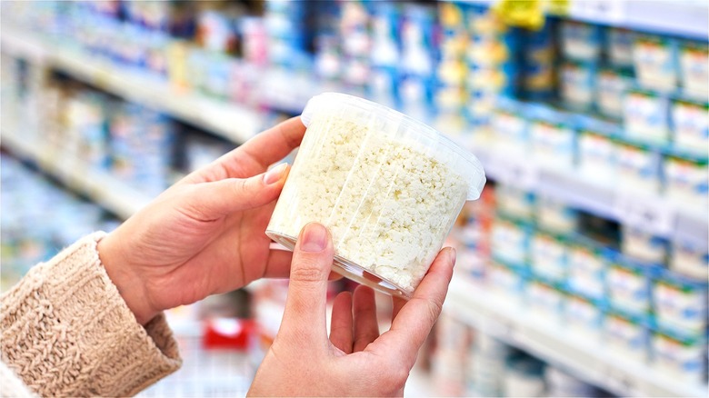 Hands holding cottage cheese in store