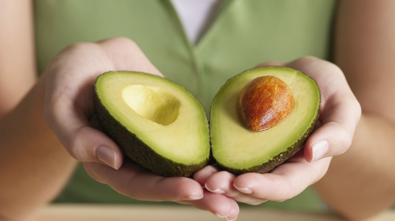 hands holding an open avocado