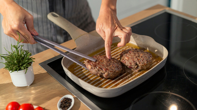 woman flipping burger in grill pan