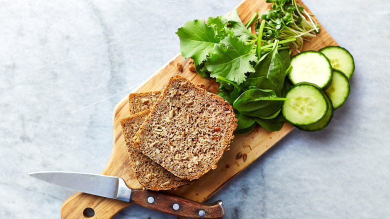 Sprouted bread on cutting board with vegetables 