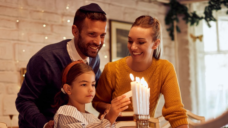 Jewish family lighting menorah