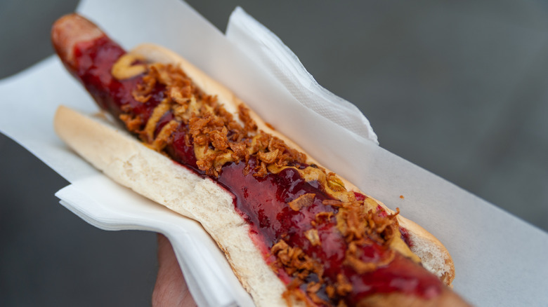 A reindeer hot dog with red sauce and onions