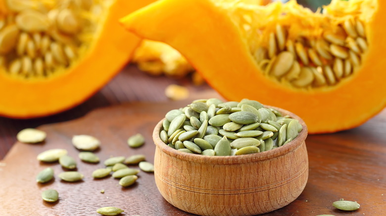 wooden cup of squash seeds with a cup open squash in background