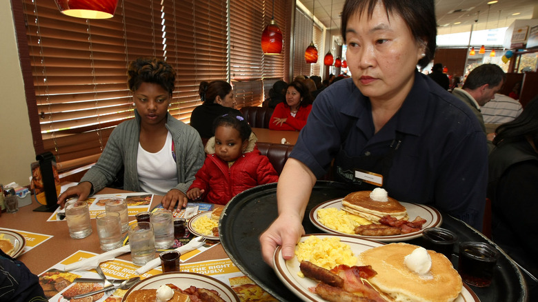 Waitress serving food to woman and child at Denny's