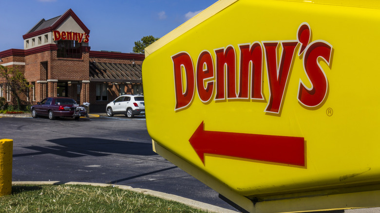 Denny's sign pointing to restaurant in distance