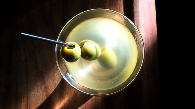 dirty martini with olives on wood background