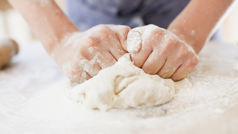 hands kneading ball of dough